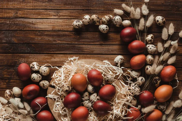 La puesta plana con los huevos de Pascua en la sección transversal del tronco del árbol sobre el fondo de madera con las orejas - foto de stock