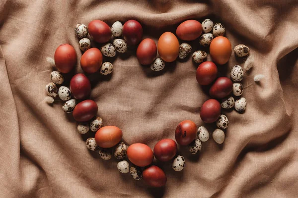 Heart shaped easter eggs and quail eggs on linen tablecloth — Stock Photo