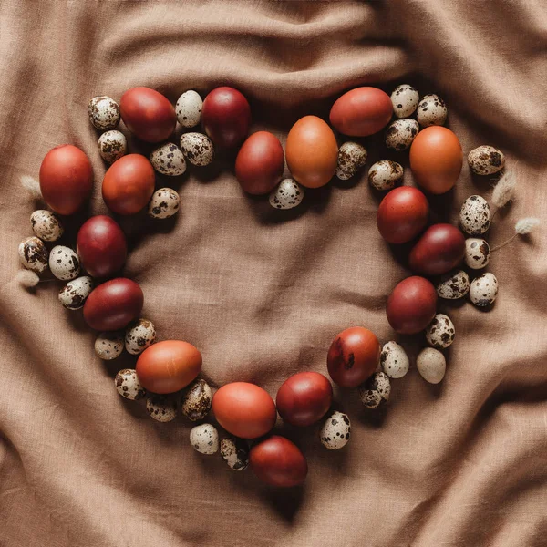 Top view of heart shaped frame made of easter eggs and quail eggs on linen tablecloth — Stock Photo