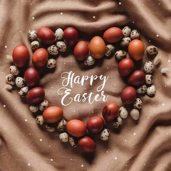 Flat lay with Happy Easter lettering and stars in heart shaped frame made of chicken and quail eggs — Stock Photo