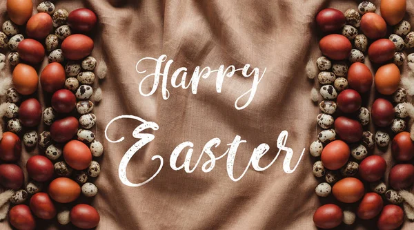Vue de dessus des oeufs peints de Pâques et des oeufs de caille sur la nappe de lin avec le lettrage de Pâques heureux — Photo de stock