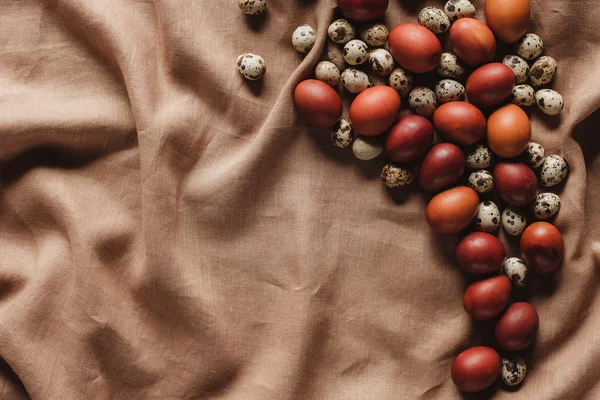 Vue de dessus des oeufs peints de Pâques et des oeufs de caille sur la nappe en lin avec espace de copie — Photo de stock