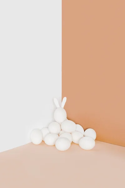 Huevos de gallina de Pascua y huevo con orejas de conejo en un fondo minimalista - foto de stock