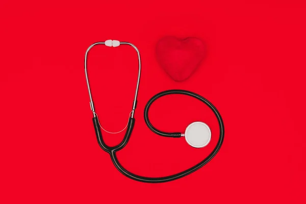 Верхний вид стетоскопа и красного сердца изолированы на красной столешнице, концепция Всемирного дня здоровья — стоковое фото