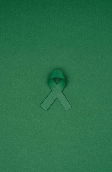 Близкий обзор зеленой ленты осведомленности о сколиозе, символа психического здоровья, изолированного на зеленой столешнице — стоковое фото