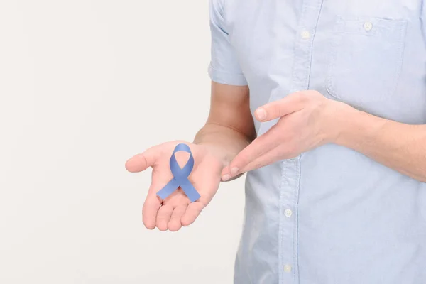 Tiro recortado del hombre que muestra cinta de conciencia azul aislado en blanco, concepto de cáncer de próstata - foto de stock