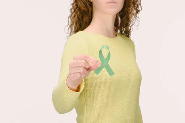 Cliché recadré d'une femme montrant un ruban vert de sensibilisation au cancer de la surrénale, sensibilisation à la recherche sur le vieillissement, trouble bipolaire à la main isolé sur blanc — Photo de stock