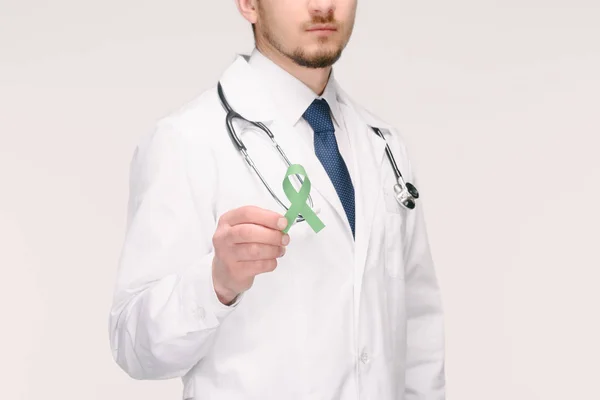 Cliché recadré d'un médecin avec stéthoscope montrant un ruban vert de sensibilisation au cancer de la surrénale, sensibilisation à la recherche sur le vieillissement, trouble bipolaire isolé sur blanc — Photo de stock