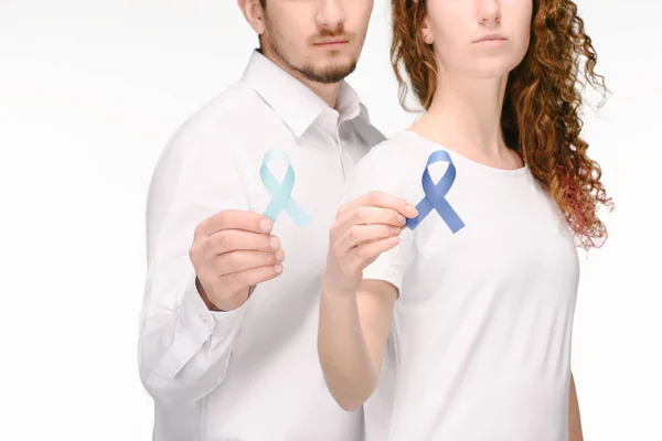 Vista parcial de pareja sosteniendo cintas de diferentes colores aislados en blanco, concepto de cáncer de colon - foto de stock