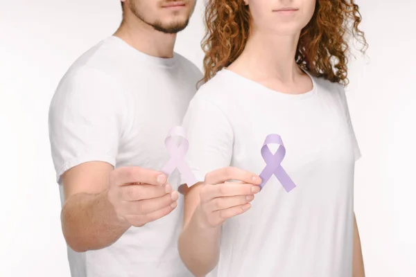 Vista parcial de la pareja que sostiene cintas de conciencia de diferentes colores aislados en blanco, concepto del día mundial de la salud - foto de stock