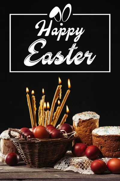 Happy easter inscription in frame, burning candles, easter cakes and painted eggs on black — Stock Photo