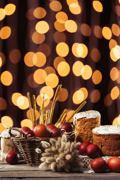 Calabazas, velas, pasteles de Pascua y huevos de pollo pintados sobre una mesa de madera con fondo bokeh - foto de stock