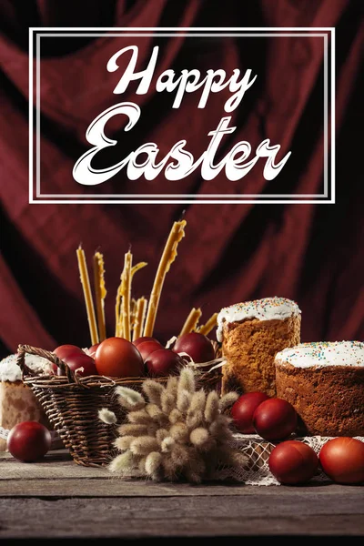 Feliz inscripción de Pascua en el marco, pasteles de Pascua, huevos de pollo pintados y velas en la mesa - foto de stock