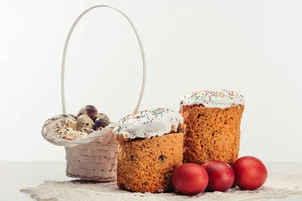 Quail eggs in basket, easter cakes and painted chicken eggs on grey — Stock Photo