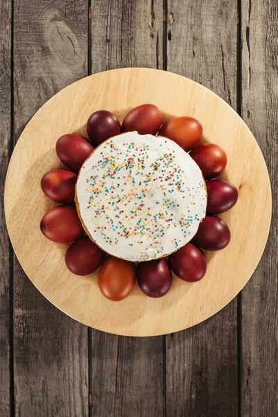 Blick von oben auf süßen hausgemachten Osterkuchen und bemalte Hühnereier auf Holztisch — Stockfoto