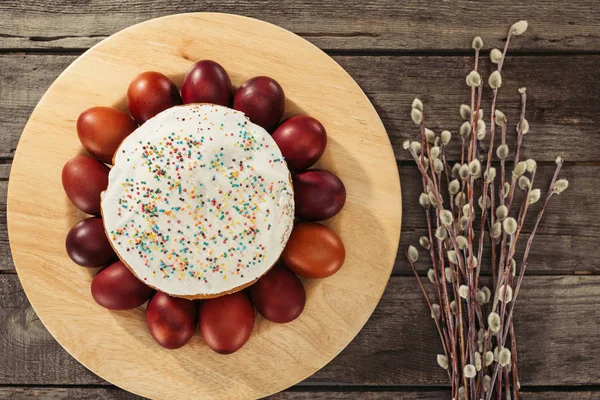 Top view of painted chicken eggs around homemade easter cake and willow twigs on wooden table — Stock Photo