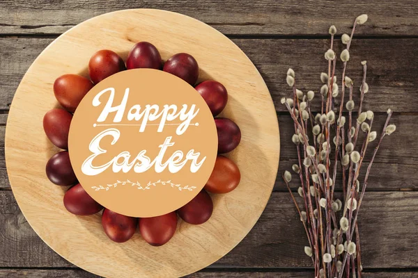 Ansicht von bemalten Ostereiern mit fröhlicher Osterbeschriftung und Kätzchen auf Holztisch — Stockfoto