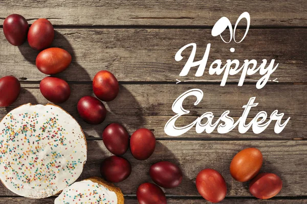 Ansicht von Osterkuchen, bemalten Eiern und fröhlicher Osterinschrift auf Holzoberfläche — Stockfoto