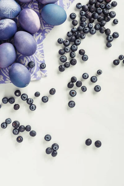 Vue du dessus des œufs de Pâques violets sur serviette et des bleuets sur gris — Photo de stock