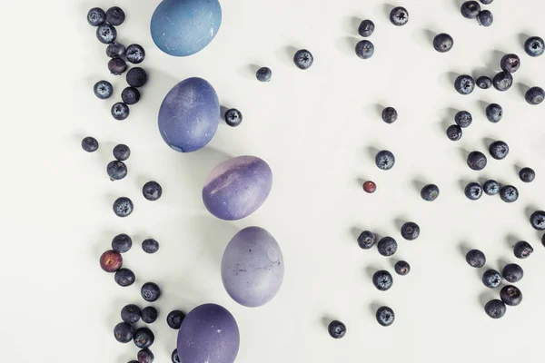 Vue du dessus des bleuets et des œufs de Pâques violets peints sur gris — Photo de stock
