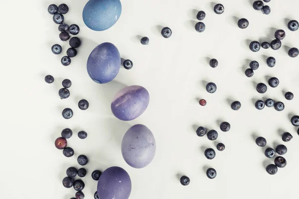 Vista dall'alto di mirtilli e uova di Pasqua dipinte viola su grigio — Foto stock