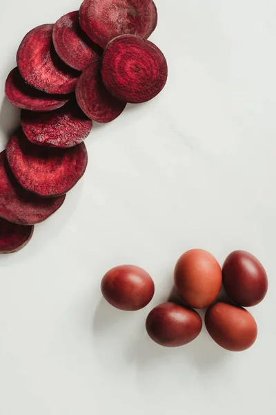 Vue de dessus des œufs de Pâques peints et des tranches de betterave sur gris — Photo de stock