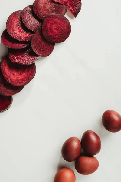 Vue de dessus des œufs de Pâques peints et des tranches de betterave sur gris — Photo de stock