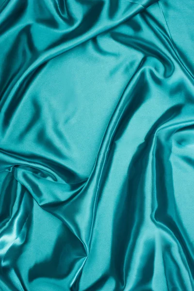 Turquoise shiny wavy satin fabric background — Stock Photo