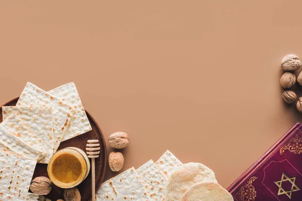 Top view of traditional book with text in hebrew and matza with honey on brown surface — Stock Photo