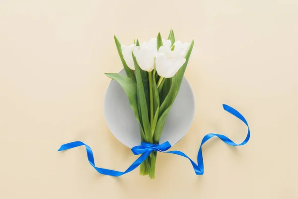Vue de dessus des tulipes blanches sur plaque isolée sur beige — Photo de stock