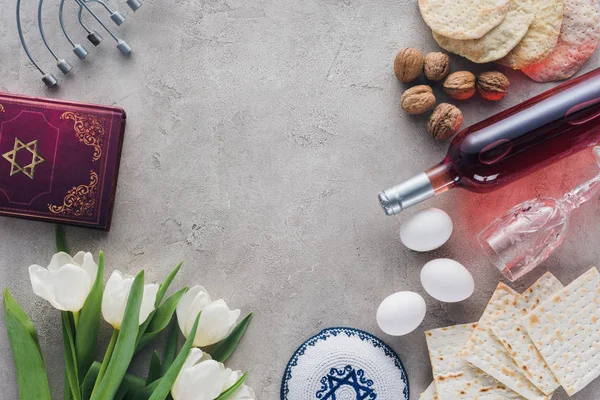 Vue du haut du livre traditionnel avec texte en hébreu, kippah et menorah sur table en béton — Photo de stock