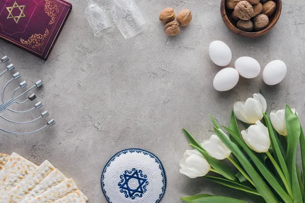 Vue du haut du livre traditionnel avec texte en hébreu, kippah et menorah sur table en béton — Photo de stock