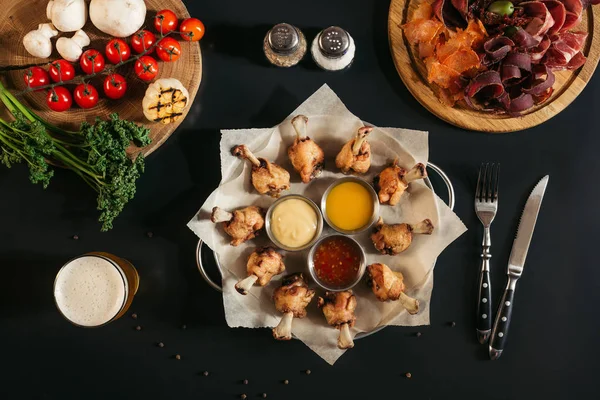 Vista dall'alto di delizioso pollo arrosto con varie salse, carne assortita e verdure su nero — Foto stock