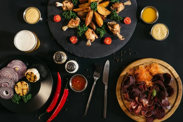 Deliziosa carne assortita con patate al forno, salse e pollo arrosto su nero — Foto stock