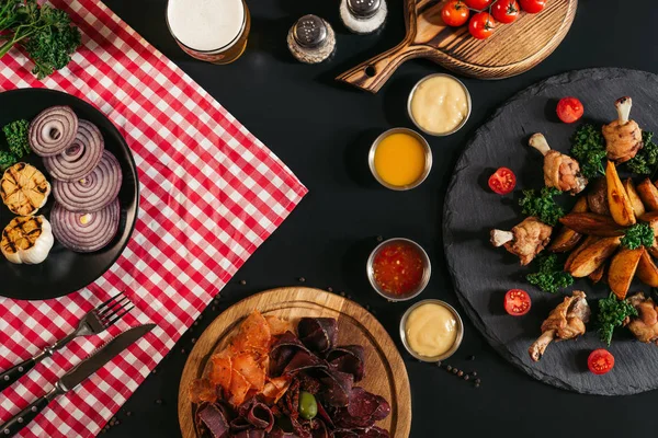 Vue du dessus de viande, légumes, sauces et pommes de terre cuites au four avec poulet rôti sur fond noir — Photo de stock