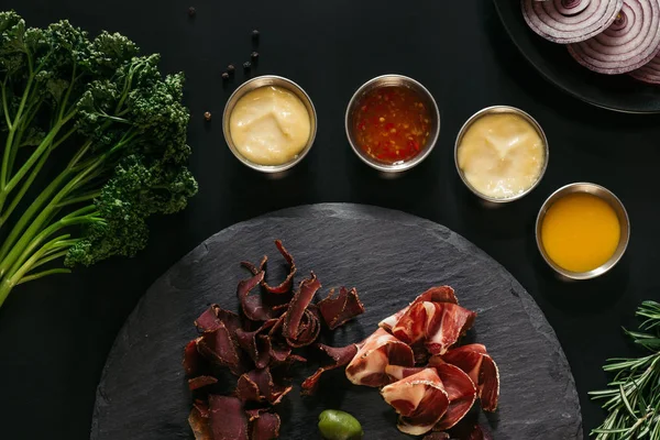 Vue de dessus de la viande artisanale gastronomique avec diverses sauces sur noir — Photo de stock