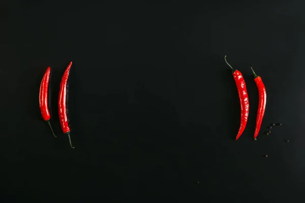 Top view of red chili peppers and peppercorns on black background — Stock Photo