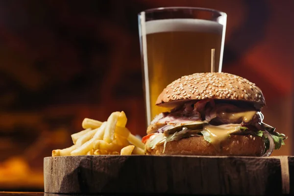 Vista de cerca de sabrosa hamburguesa con pavo, papas fritas y vaso de cerveza - foto de stock