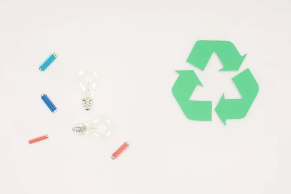 Vue de dessus des ampoules et des batteries avec panneau de recyclage sur blanc — Photo de stock