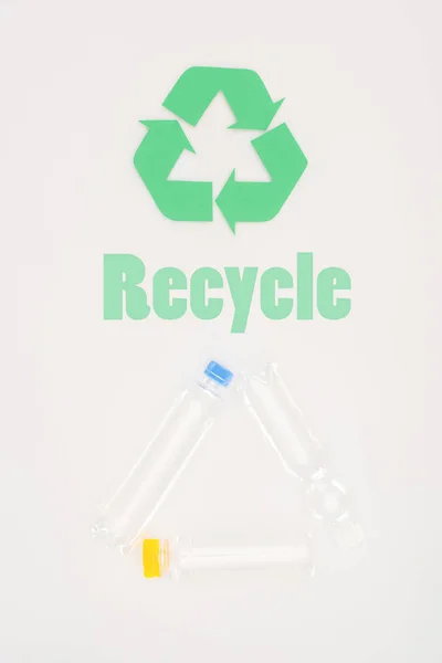 Vista superior de botellas de plástico con cartel de reciclaje en blanco - foto de stock