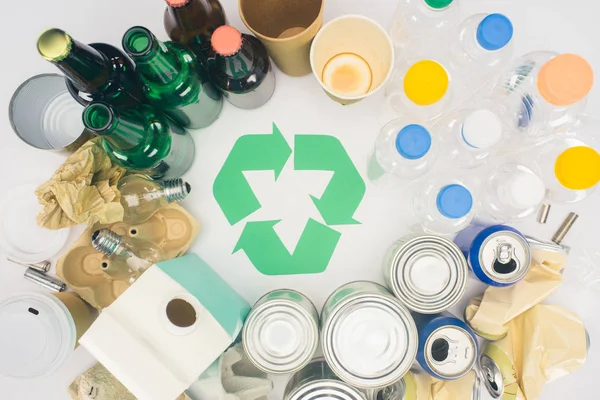 Top view of different types of trash with recycle sign on white — Stock Photo
