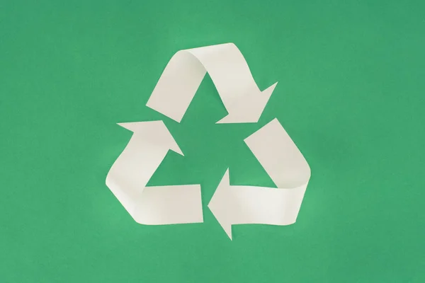 Top view of white arrows recycle sign on green — Stock Photo