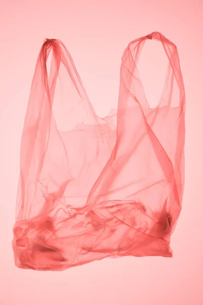 Saco de plástico amassado com garrafa dentro sob luz tonificada rosa pastel — Fotografia de Stock