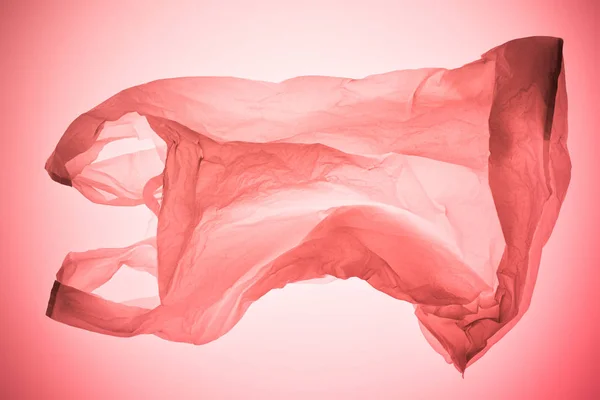 Saco de plástico transparente amassado sob luz tonificada rosa pastel — Fotografia de Stock