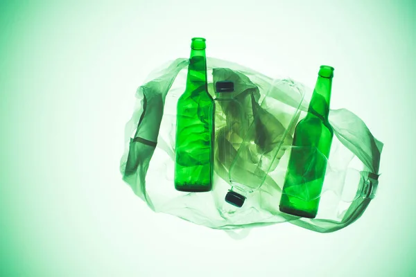Прозрачный пластиковый пакет с различными бутылками под зеленым тоном — стоковое фото