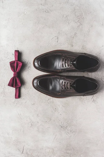 Top view of pair of shoes and bow tie for wedding on gray surface — Stock Photo