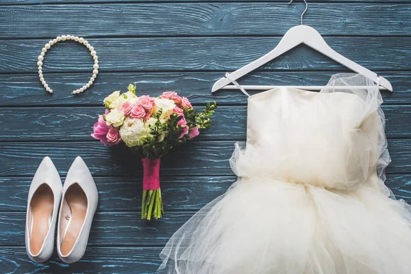 Верхний вид свадебного букета и платья на деревянный темно-синий стол — стоковое фото