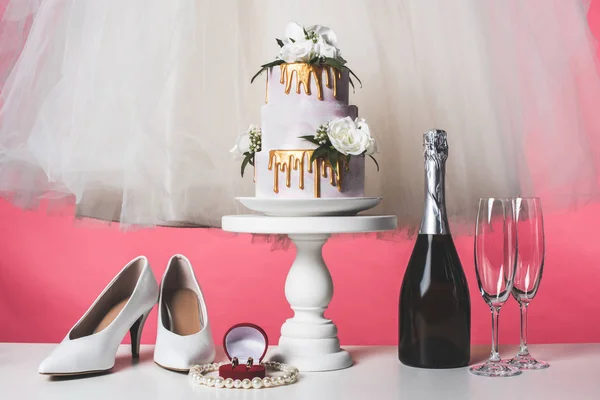 Paar Schuhe, Hochzeitstorte und Champagner auf rosa — Stockfoto