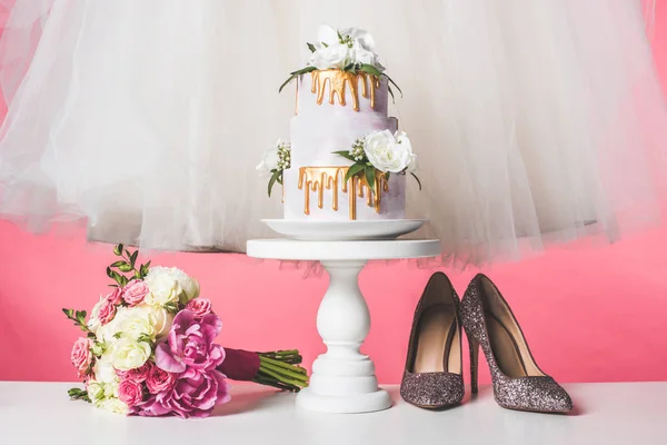 Paire de chaussures, bouquet de mariage, gâteau et robe blanche isolé sur rose — Photo de stock
