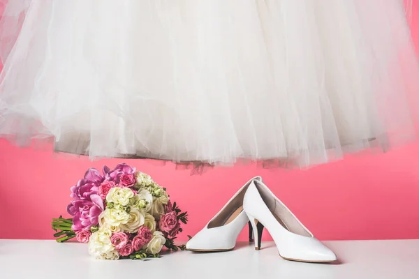 Par de zapatos, ramo de bodas y vestido blanco aislado en rosa - foto de stock